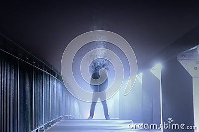 A conceptual digital art picture of a man who`s head has disintegrated and turned into smoke, standing on a foggy path at night. W Stock Photo