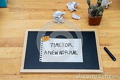 Conceptual hand writing showing Time For A New Normal, on white paperclip hold written chalkboard on wooden deck Stock Photo
