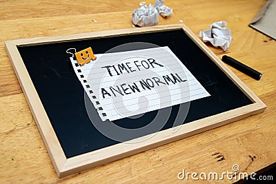 Conceptual hand writing showing Time For A New Normal, on white paperclip hold written chalkboard on wooden deck Stock Photo