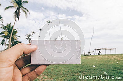 Conceptual image, cropped hand holding white frame canvas over blurred village background Stock Photo