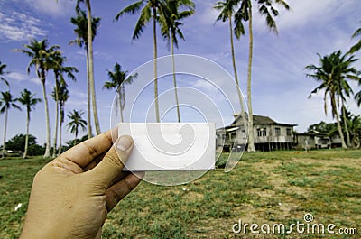 Conceptual image, cropped hand holding white frame canvas over blurred village background Stock Photo