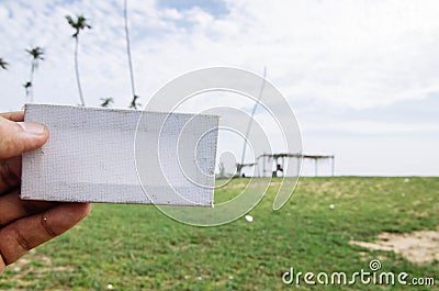 Conceptual image, cropped hand holding white frame canvas over blurred village background Stock Photo