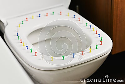 Conceptual image of a hemorrhoid disease with multi-colored thumbtacks on toilet bowl cover Stock Photo