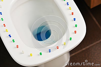 Conceptual image of a hemorrhoid disease with multi-colored thumbtacks on toilet bowl cover Stock Photo