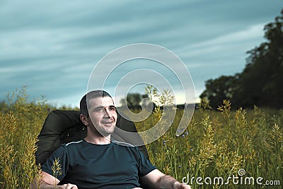 Conceptual image of watching movies in modern technologies, a young man sits in a comfortable chair on the nature under the open Stock Photo