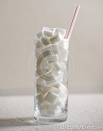 Conceptual macro still life image of refreshment glass full of sugar cubes and straw isolated on white background in glucose addic Stock Photo