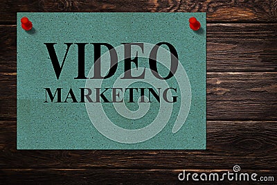 Conceptual messages `VIDEO MARKETING` written on green paper stands as an advertisement on a wooden surface. Stock Photo