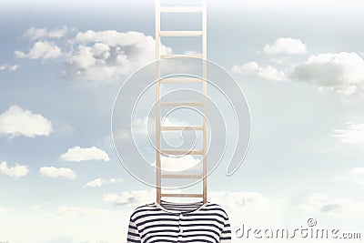 A conceptual photo with a ladder coming out of a person`s body and climbing towards a cloudy sky Stock Photo