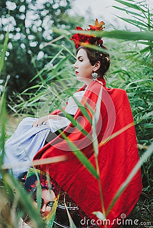 Conceptual portrait of beautiful young woman with red lips, red flowers in hair, sitting in wheel chair. Stock Photo