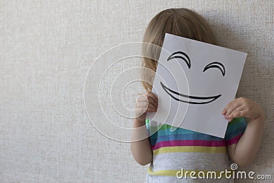 Conceptual portrait smiley. A small child covers his face with a funny mask. smiley. Stock Photo