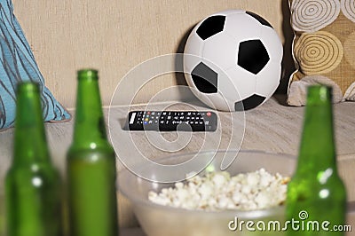 Conceptual watching football game at sofa on television with beer bottles and popcorn bowl in friends enjoying soccer game TV Stock Photo