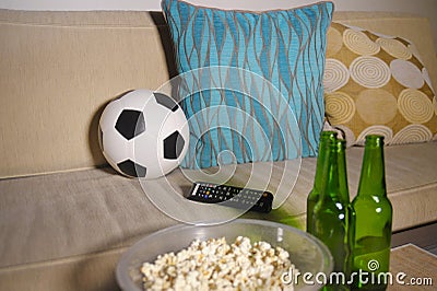 Conceptual watching football game at sofa on television with beer bottles and popcorn bowl in friends enjoying soccer game TV Stock Photo