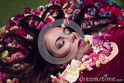 Conceptual studio portrait girl. Artificial flowers and a green background Stock Photo