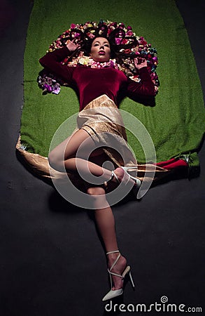 Conceptual studio portrait girl. Artificial flowers and a green background Stock Photo