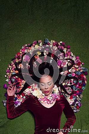 Conceptual studio portrait girl. Artificial flowers and a green background Stock Photo