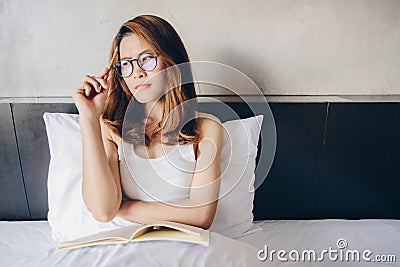 Portrait of young happiness Asian woman sitting on bed, holding a notebook and pencil on her hands, ready to work or writing somet Stock Photo