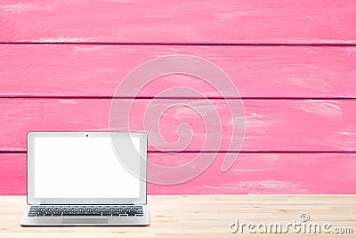 Conceptual workspace or business concept. Laptop computer with blank white screen on light wooden table against painted pink woode Stock Photo