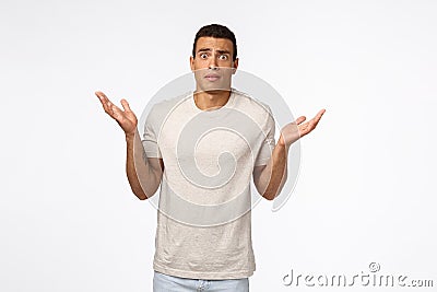 Concerned and alarmed tanned muscline young man standing shocked and confused, shrugging with hands spread sideways Stock Photo