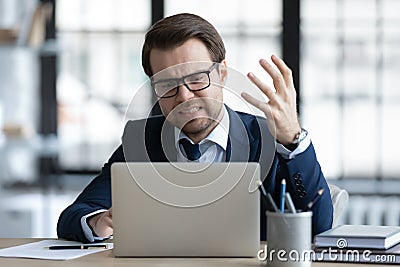 Concerned annoyed office employee upset about problems with laptop Stock Photo