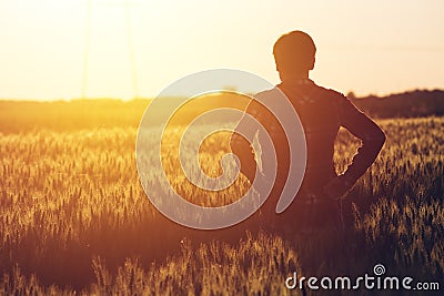 Concerned female agronomist standing in cultivated wheat crops f Stock Photo