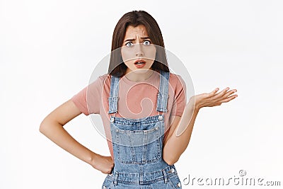 Concerned, freak-out girl look puzzled and frustrated, shrugging raise one hand in dismay, demanding answers, look Stock Photo