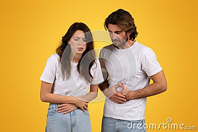 Concerned man and woman with pained expressions holding their stomachs Stock Photo