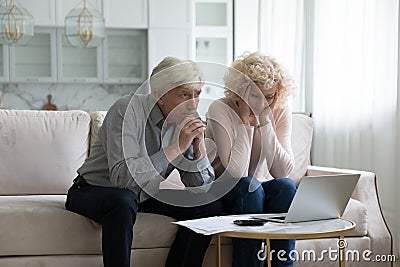 Concerned mature husband and wife frustrated about overspending family budget Stock Photo