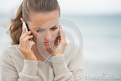 Concerned woman talking cell phone on beach Stock Photo
