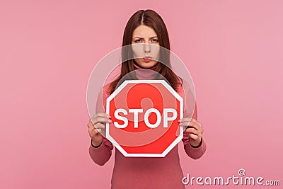 Concerned worried woman holding stop sign in hands, warning about compliance with rules, traffic laws Stock Photo