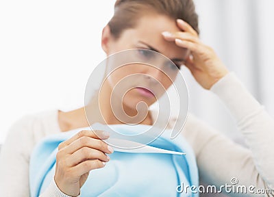 Concerned young woman holding thermometer Stock Photo