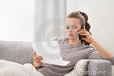 Concerned young woman with letter and talking cell phone Stock Photo