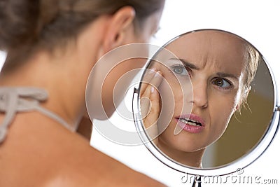 Concerned young woman looking in mirror Stock Photo