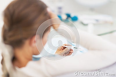 Concerned young woman looking on thermometer Stock Photo