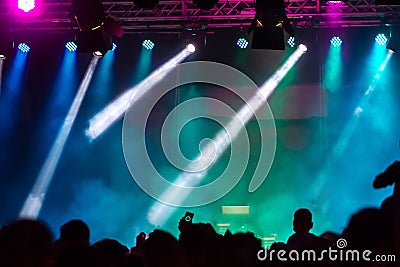 Concert crowd attending a concert, people silhouettes are visible, backlit by stage lights. Raised hands and smart phones are visi Stock Photo