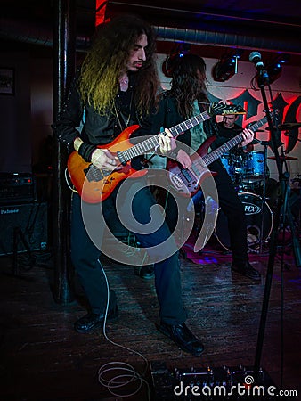 Concert photo of a rock band with guitarist, bassist, and drummer Editorial Stock Photo