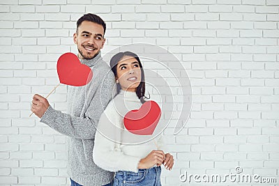 Concert Valentine`s Day. Young couple with hearts in hands on a white brick background Stock Photo