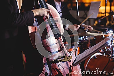 Concert view of a contrabass violoncello player with vocalist and musical during jazz orchestra band performing music, Stock Photo