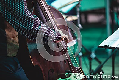 Concert view of a contrabass violoncello player with vocalist and musical during jazz orchestra band performing music, Stock Photo