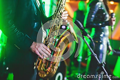 Concert view of a saxophone player with vocalist and musical jazz band in the background Stock Photo