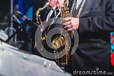 Concert view of a saxophonist, saxophone sax player with vocalist and musical during jazz orchestra performing music on stage Stock Photo