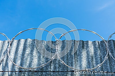 Concertina wire installed atop of metal fence Stock Photo