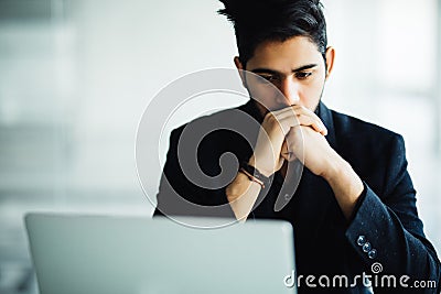 Concetrated indian man smiling and working at office Stock Photo