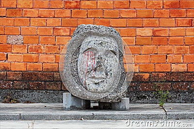 Concrete artifact along the city street with a brick wall background. Stock Photo