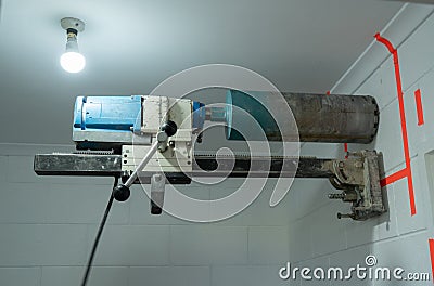 Concrete coring drill bolted to interior breeze block wall Stock Photo