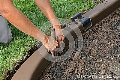 Concrete curb edging being shaped for smoothness in a flower bed Stock Photo