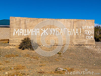 concrete fence with large inscription translating from Kyrgyz car washing prohibited, fine 500 som Editorial Stock Photo