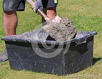 Concrete mortar mixed in black bucket with spade by worker in garden, close up Stock Photo