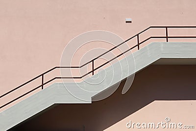 Concrete staircase with brown metallic railing on pink painted facade Stock Photo