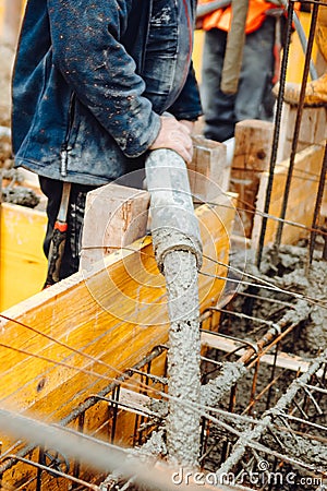 works at the construction site. Construction workers pour liquid concrete from cement concrete hose Stock Photo