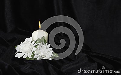 Condolence card. White burning candle and white flowers on a black background, free space for text Stock Photo